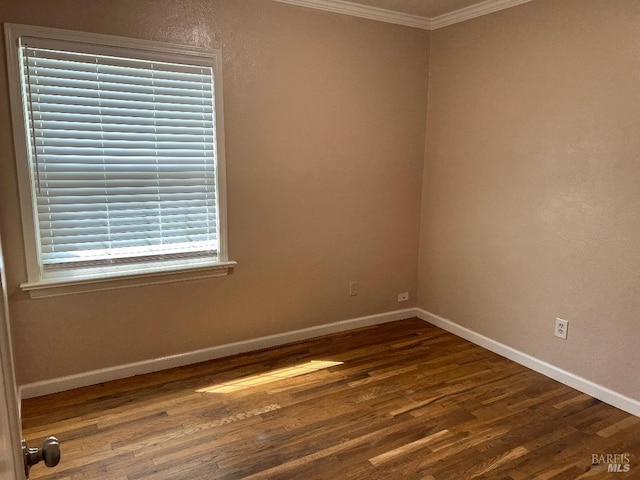 spare room featuring baseboards, crown molding, and wood finished floors