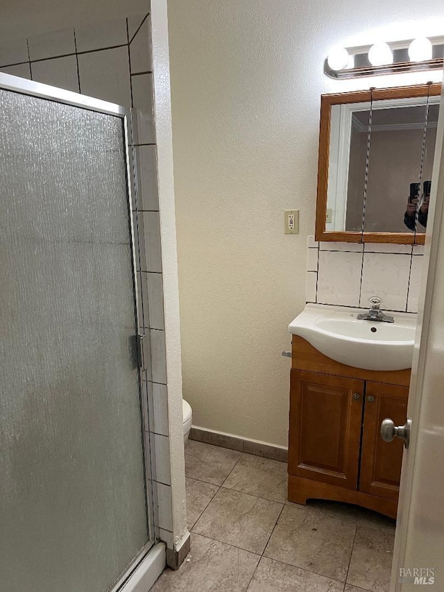 bathroom featuring a stall shower, toilet, vanity, tile patterned flooring, and baseboards