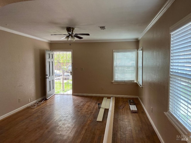 spare room with visible vents, crown molding, wood finished floors, and a ceiling fan
