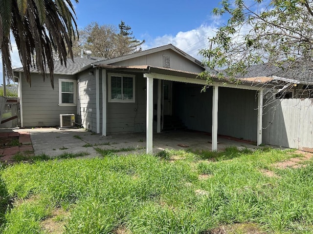 back of property featuring central AC, a carport, and fence