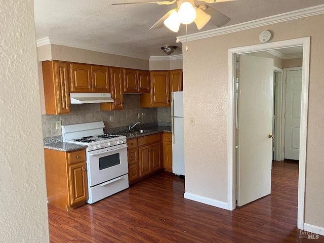 kitchen featuring white appliances, ceiling fan, brown cabinets, dark wood finished floors, and under cabinet range hood