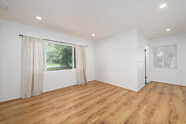 spare room with recessed lighting, light wood finished floors, and baseboards