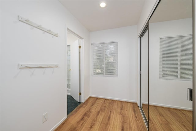 corridor with baseboards, light wood finished floors, and recessed lighting