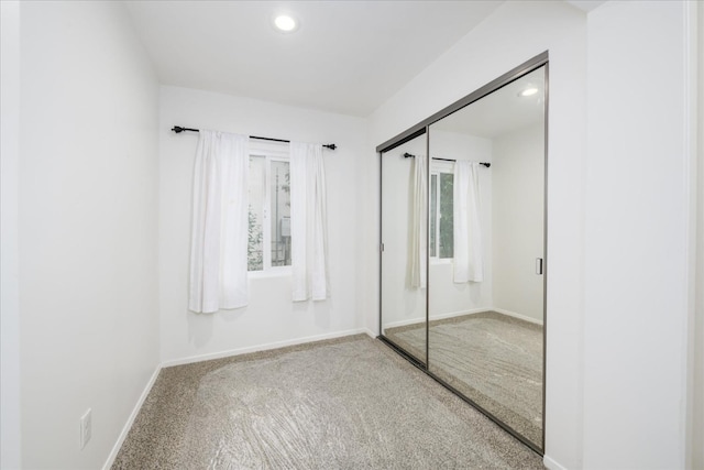 unfurnished bedroom featuring a closet, carpet flooring, baseboards, and recessed lighting