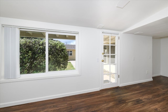 spare room featuring dark wood-type flooring and baseboards