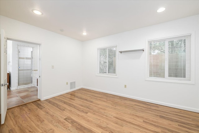 spare room featuring a wealth of natural light, visible vents, light wood-type flooring, and baseboards
