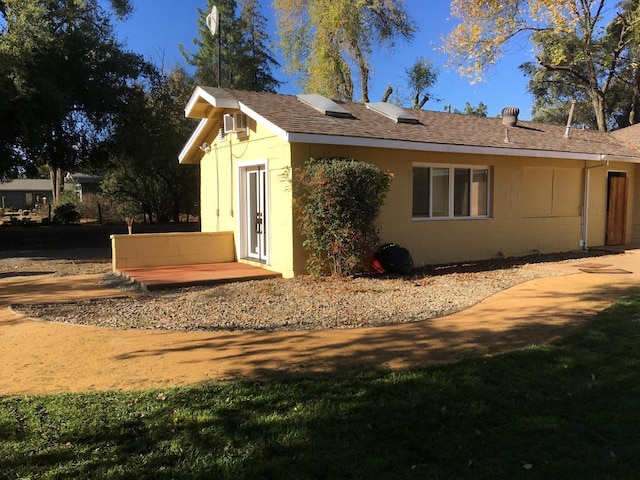 rear view of house with concrete block siding and a shingled roof
