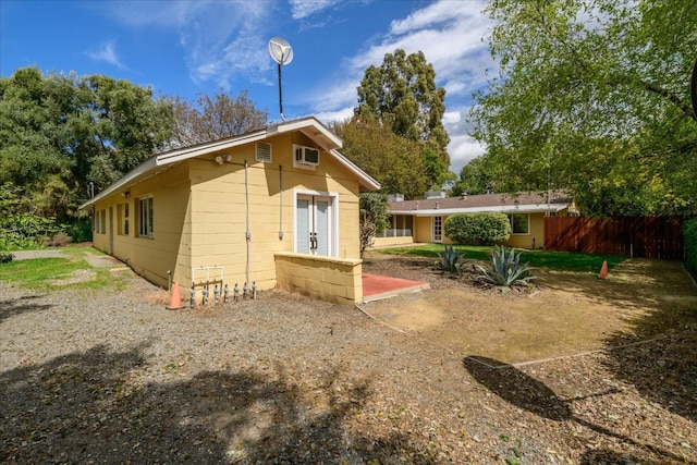 back of house with concrete block siding and fence