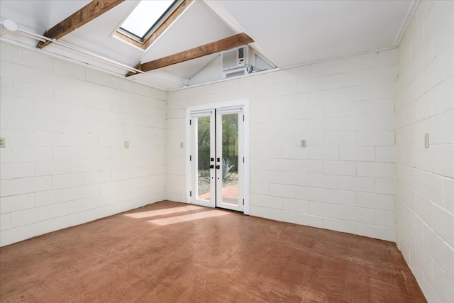 spare room featuring french doors, concrete block wall, and lofted ceiling with skylight