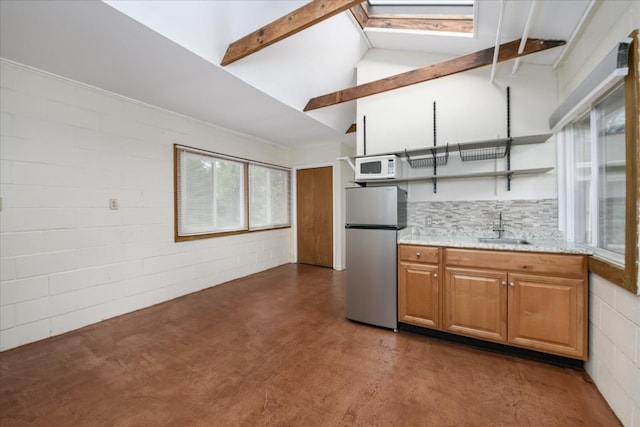 kitchen with concrete floors, open shelves, a sink, freestanding refrigerator, and white microwave