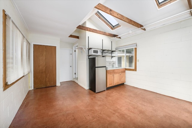 kitchen featuring a sink, light countertops, freestanding refrigerator, white microwave, and a skylight