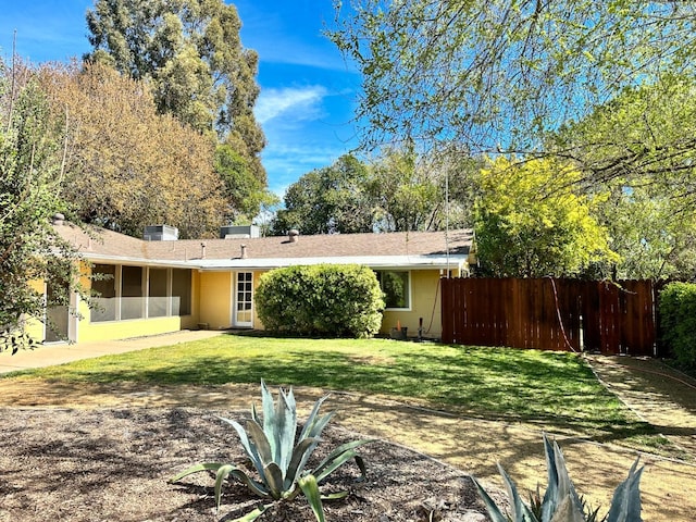 back of property featuring a sunroom, a yard, and fence
