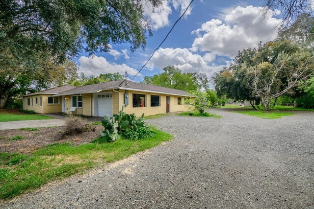 ranch-style home with a garage and gravel driveway