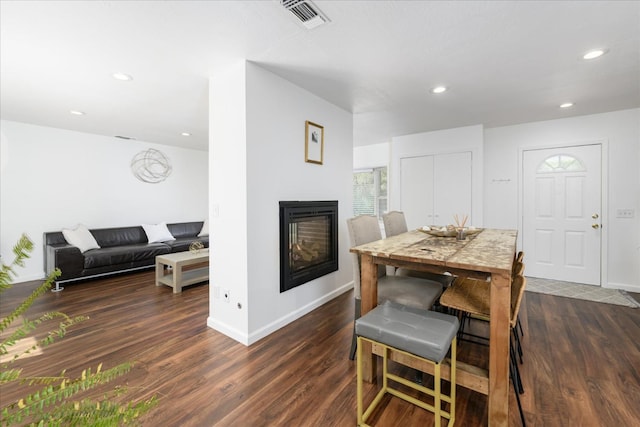 dining room featuring visible vents, baseboards, dark wood finished floors, and a multi sided fireplace
