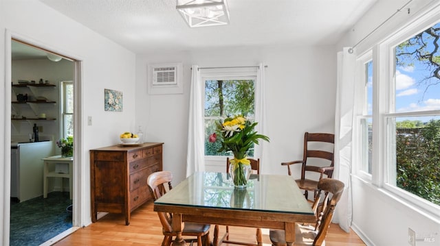 dining space featuring a wall mounted air conditioner and light wood finished floors