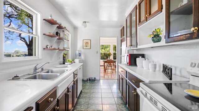 kitchen with light countertops, open shelves, white appliances, and a sink