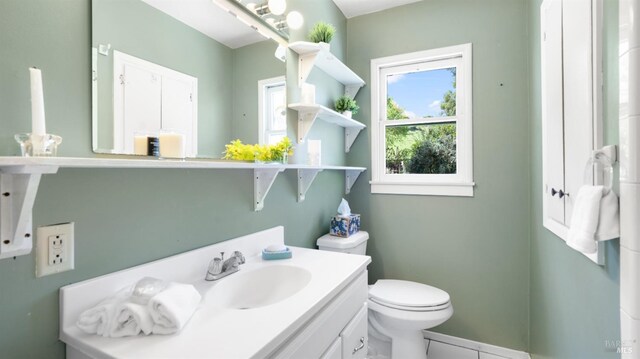 half bathroom with vanity, tile patterned flooring, and toilet