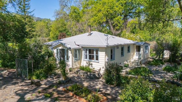 view of front of house featuring entry steps, a chimney, and a wooded view