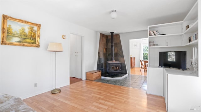 living room featuring baseboards, a wood stove, and wood finished floors