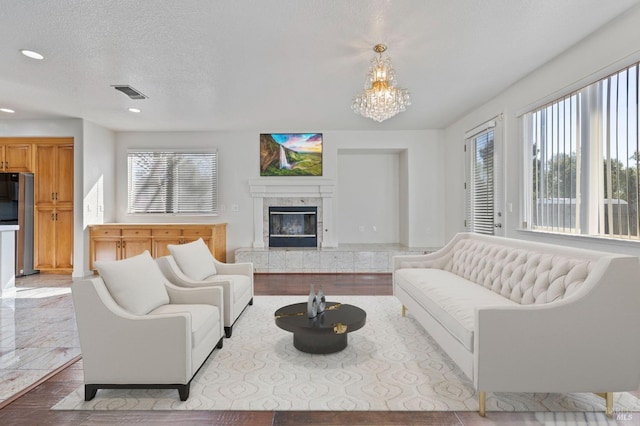 living area with a textured ceiling, visible vents, a premium fireplace, recessed lighting, and an inviting chandelier