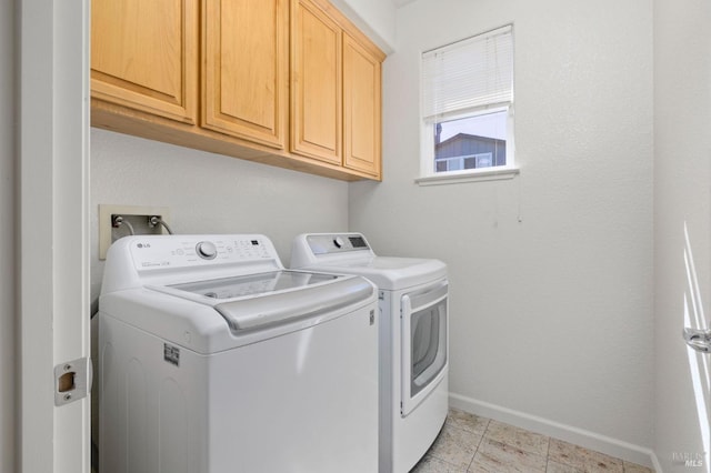 laundry area featuring baseboards, cabinet space, washer and clothes dryer, and light tile patterned floors