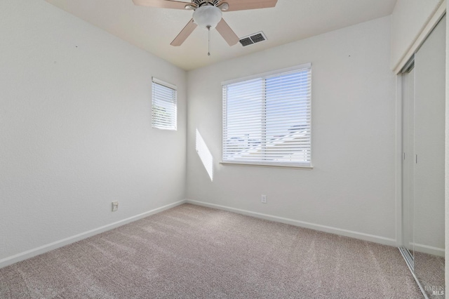 unfurnished bedroom with a closet, a ceiling fan, light carpet, baseboards, and visible vents