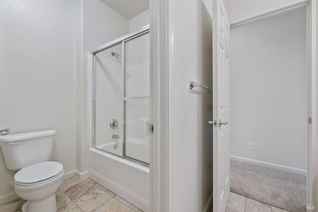 bathroom featuring baseboards, enclosed tub / shower combo, and toilet
