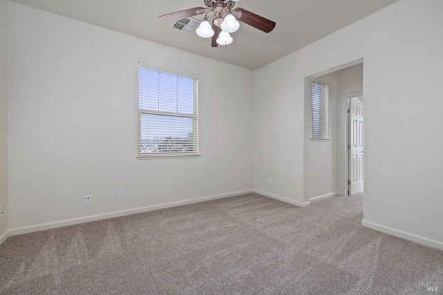 empty room featuring baseboards, visible vents, ceiling fan, and carpet