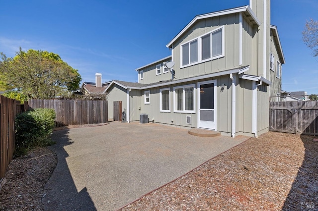 rear view of property with central air condition unit, a fenced backyard, board and batten siding, and a patio area