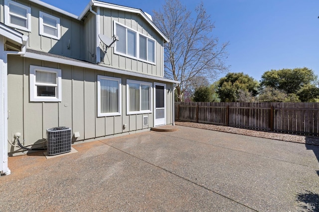 rear view of property with a patio, central AC unit, board and batten siding, and fence private yard
