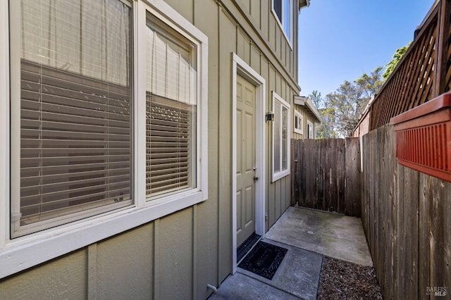 view of exterior entry featuring fence and board and batten siding