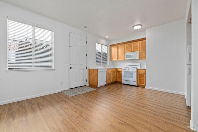 kitchen with light countertops, baseboards, light wood-style floors, and white appliances