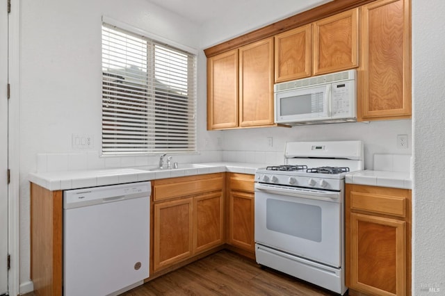 kitchen with dark wood finished floors, white appliances, tile counters, and a sink