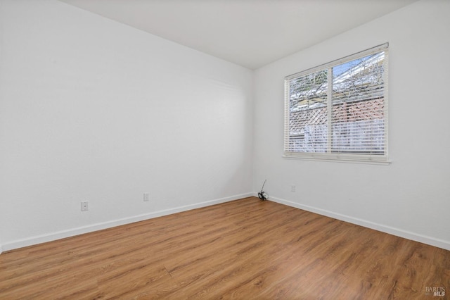 spare room featuring baseboards and light wood finished floors