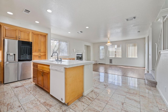 kitchen featuring a fireplace, stainless steel fridge, dishwasher, tile countertops, and visible vents