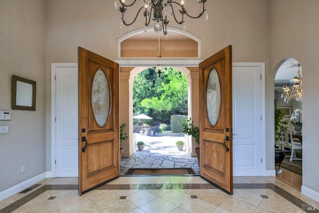 entryway featuring baseboards, a high ceiling, visible vents, and an inviting chandelier