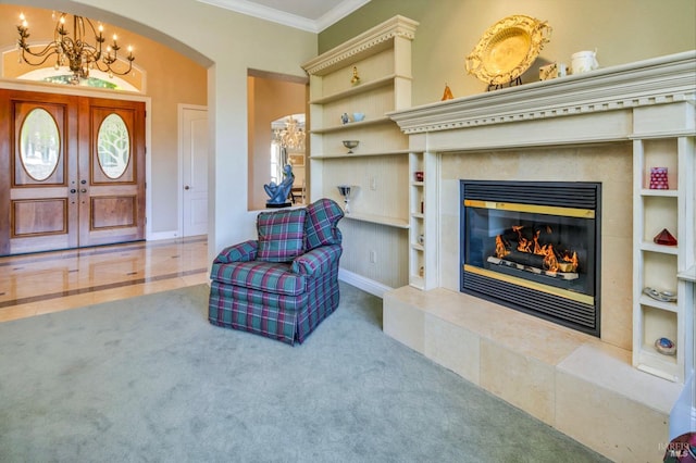 sitting room with carpet flooring, a notable chandelier, crown molding, and a tiled fireplace