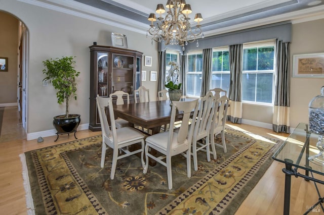 dining area with crown molding, baseboards, arched walkways, a notable chandelier, and wood finished floors