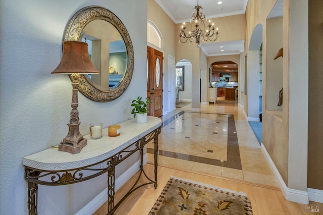 interior space featuring baseboards, wood finished floors, crown molding, and arched walkways