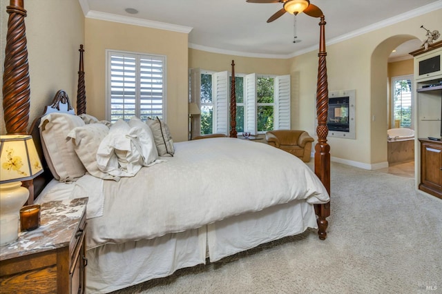 carpeted bedroom with arched walkways, crown molding, and multiple windows