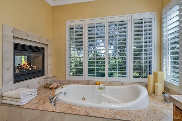 full bath with vanity, a premium fireplace, a healthy amount of sunlight, and a whirlpool tub