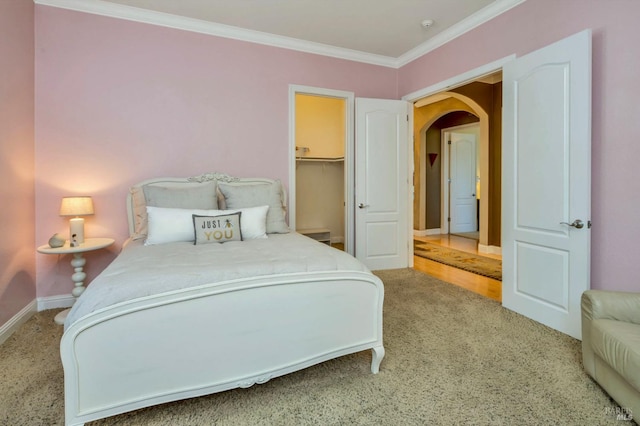 carpeted bedroom with arched walkways, ornamental molding, and baseboards