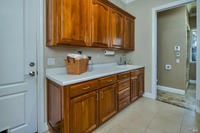 kitchen featuring light tile patterned flooring, light countertops, visible vents, baseboards, and a sink