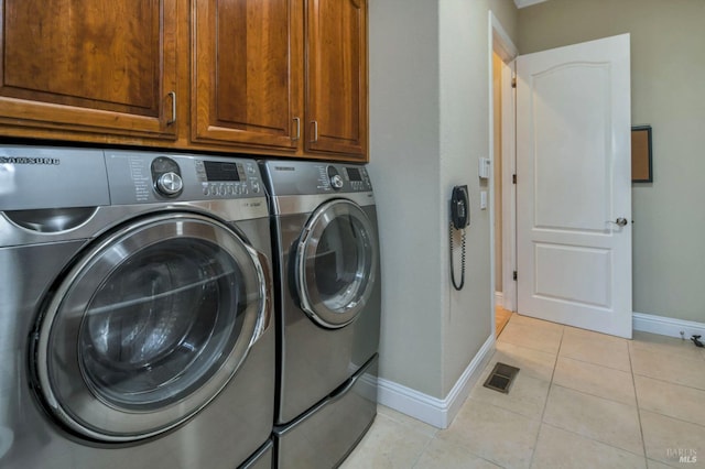 laundry room with independent washer and dryer, light tile patterned floors, baseboards, visible vents, and cabinet space
