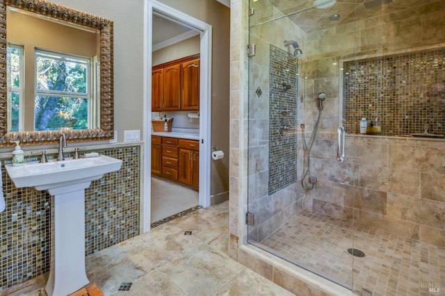 bathroom featuring a stall shower, a sink, ornamental molding, and tile walls