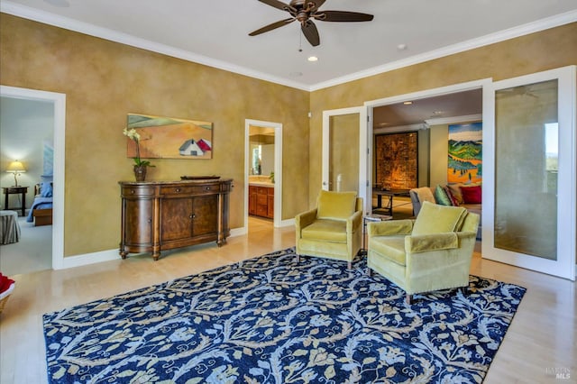 sitting room with crown molding, french doors, a ceiling fan, wood finished floors, and baseboards