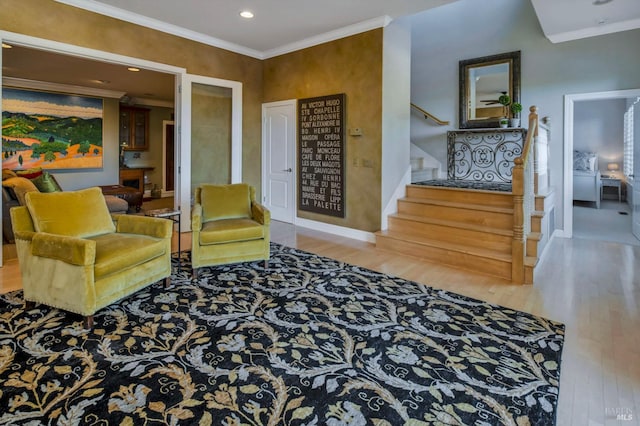 sitting room featuring baseboards, stairway, wood finished floors, and ornamental molding