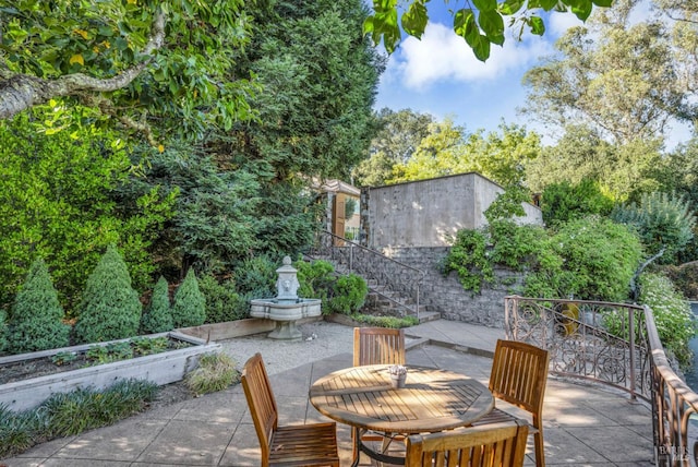 view of patio / terrace featuring stairs, outdoor dining space, and a vegetable garden