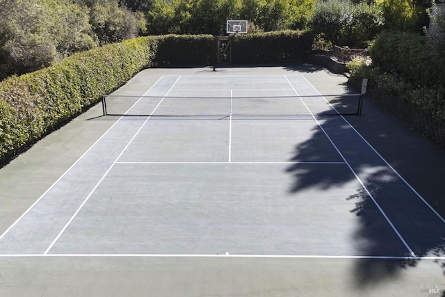 view of tennis court with community basketball court and fence
