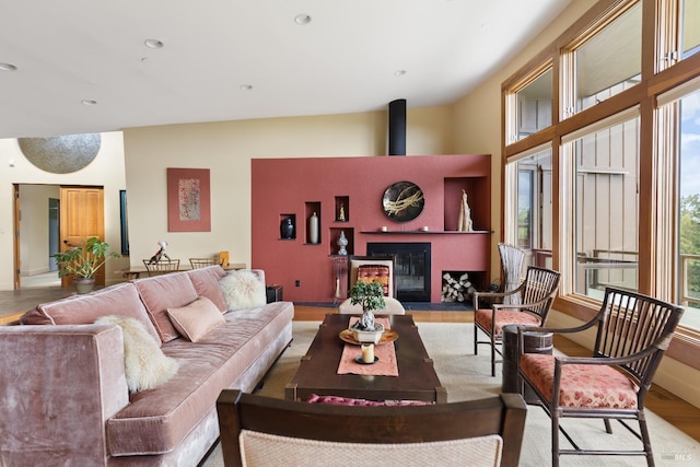 living area featuring a glass covered fireplace, recessed lighting, and wood finished floors